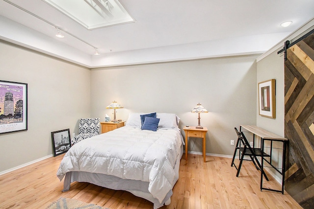 101 W Liberty St Unit 320, Ann Arbor, MI 48104 - bedroom with rail lighting, a barn door, light wood finished floors, and baseboards
