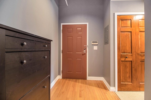 foyer entrance with light wood-type flooring, electric panel, and baseboards