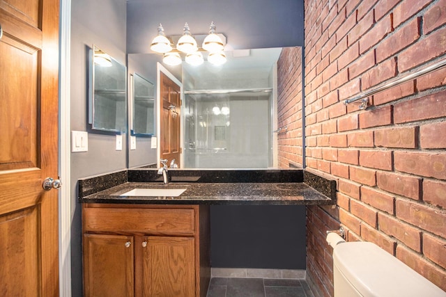 full bathroom featuring a shower with shower door, toilet, vanity, tile patterned flooring, and brick wall