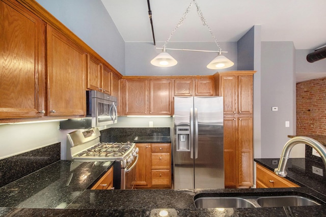 kitchen featuring stainless steel appliances, a sink, brown cabinetry, dark stone countertops, and lofted ceiling