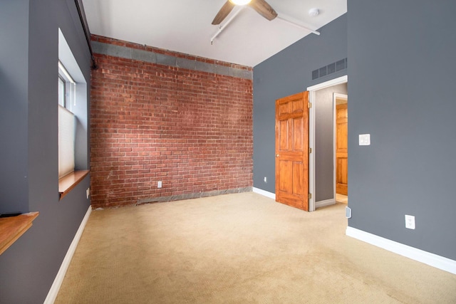 empty room with brick wall, a ceiling fan, carpet, baseboards, and a smoke detector