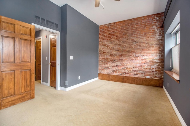 empty room featuring light colored carpet, a ceiling fan, brick wall, and baseboards