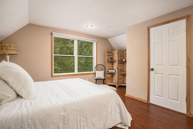 bedroom featuring lofted ceiling, dark wood-style flooring, and baseboards