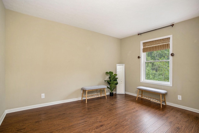 spare room featuring dark wood-style floors and baseboards