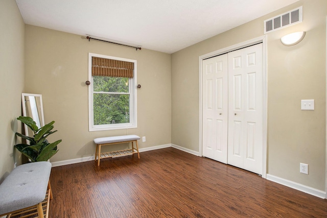 bedroom with wood finished floors, baseboards, and a closet