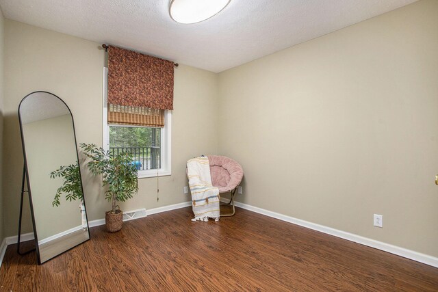 unfurnished room with wood finished floors, baseboards, and a textured ceiling