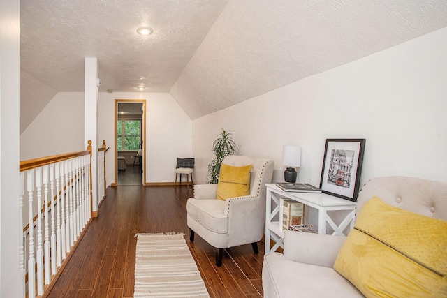 living area with a textured ceiling, wood finished floors, lofted ceiling, and baseboards