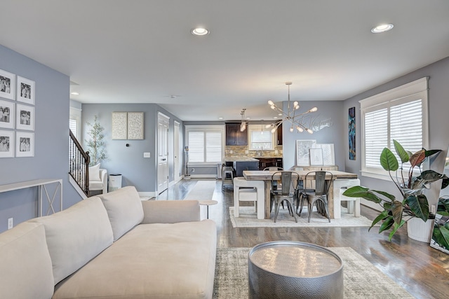 living area with baseboards, recessed lighting, wood finished floors, a chandelier, and stairs