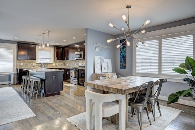 dining area featuring a chandelier, light wood finished floors, baseboards, and recessed lighting
