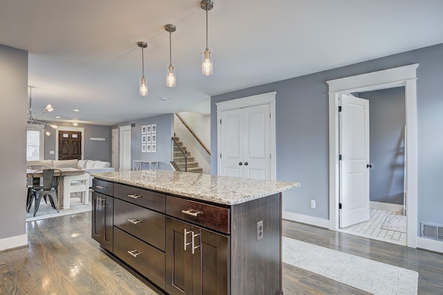 kitchen with dark brown cabinetry, dark wood-type flooring, baseboards, hanging light fixtures, and open floor plan