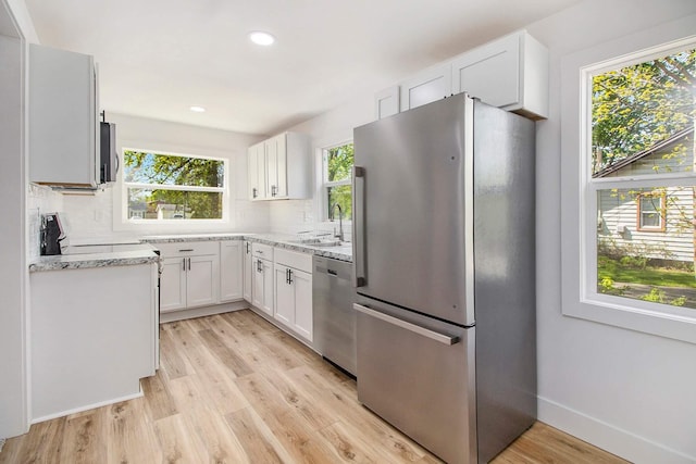 kitchen with appliances with stainless steel finishes, a sink, light wood-style floors, tasteful backsplash, and recessed lighting