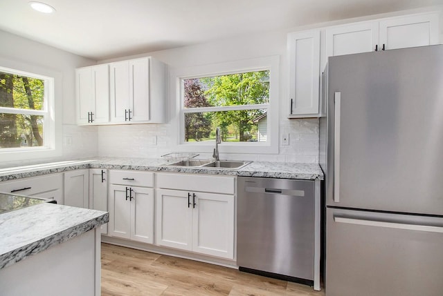 kitchen with appliances with stainless steel finishes, a sink, white cabinetry, decorative backsplash, and recessed lighting