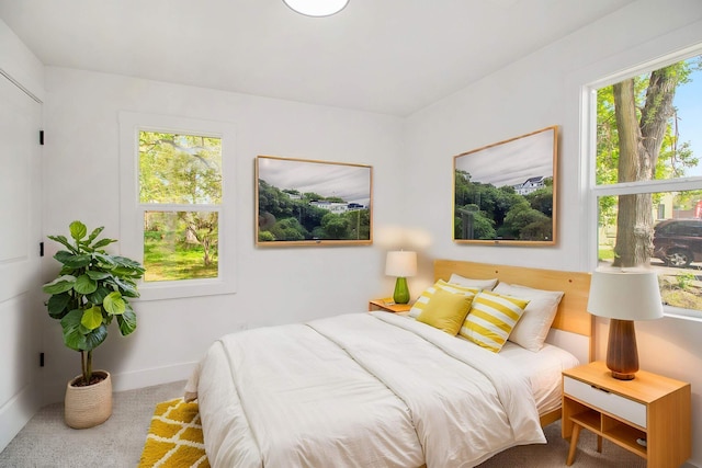 carpeted bedroom featuring multiple windows and baseboards