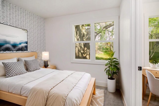 carpeted bedroom featuring an accent wall and baseboards