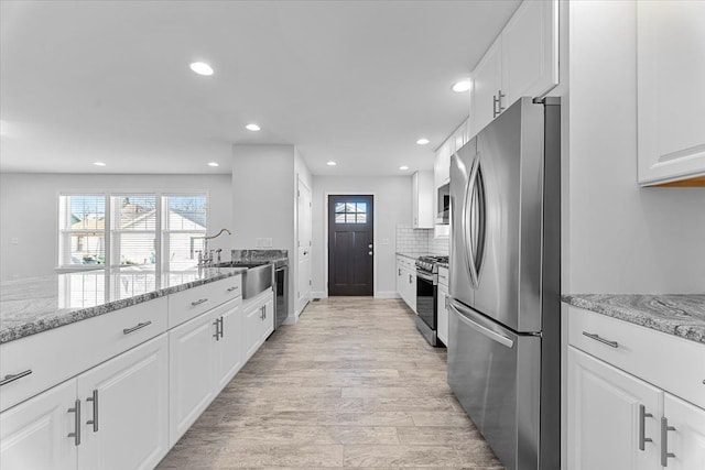 1132 Superior Blvd, Wyandotte, MI 48192 - kitchen with stainless steel appliances, a sink, recessed lighting, white cabinetry, and light stone counters