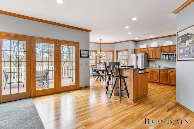 7620 Spring Point Ct NE, Rockford, MI 49341 - kitchen featuring stainless steel appliances, a chandelier, light wood-type flooring, a kitchen bar, and decorative backsplash