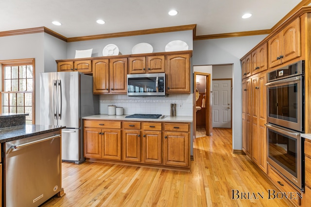 7620 Spring Point Ct NE, Rockford, MI 49341 - kitchen featuring stainless steel appliances, ornamental molding, light wood-style floors, decorative backsplash, and brown cabinets