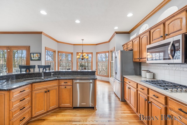 7620 Spring Point Ct NE, Rockford, MI 49341 - kitchen with appliances with stainless steel finishes, a sink, light wood finished floors, a chandelier, and plenty of natural light