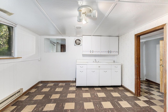 721 W Washington St, Ann Arbor, MI 48103 - kitchen featuring baseboard heating, dark flooring, light countertops, white cabinetry, and a sink