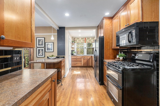 721 W Washington St, Ann Arbor, MI 48103 - kitchen with black appliances, light wood-type flooring, brown cabinets, recessed lighting, and decorative backsplash