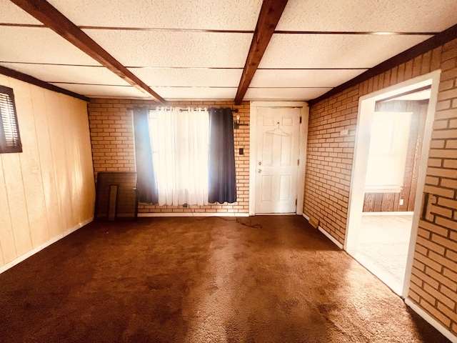 12791 Coleen Ave, Warren, MI 48089 - carpeted empty room featuring brick wall, wood walls, and beamed ceiling