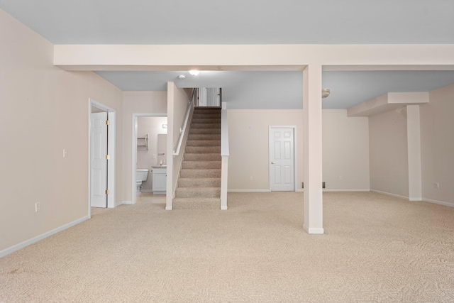 finished basement with light colored carpet, stairs, and baseboards