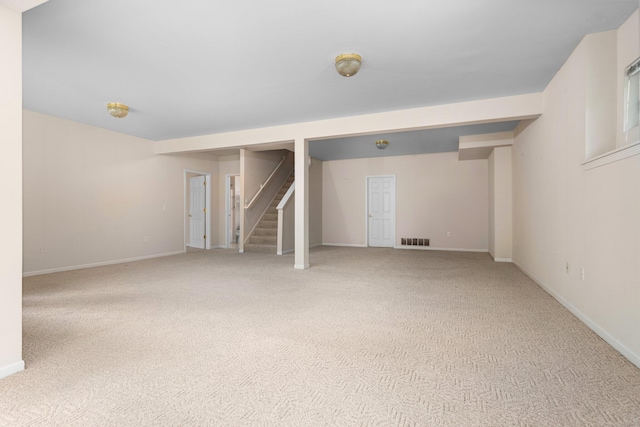 finished below grade area with light colored carpet, stairs, and baseboards