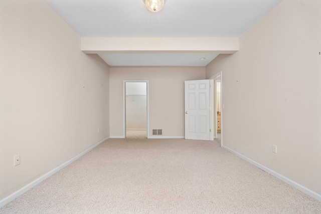 spare room featuring baseboards and light colored carpet
