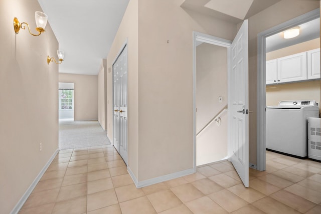 corridor with washer / clothes dryer, light tile patterned floors, and baseboards