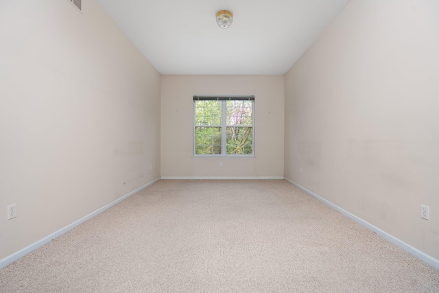 spare room with light colored carpet and baseboards