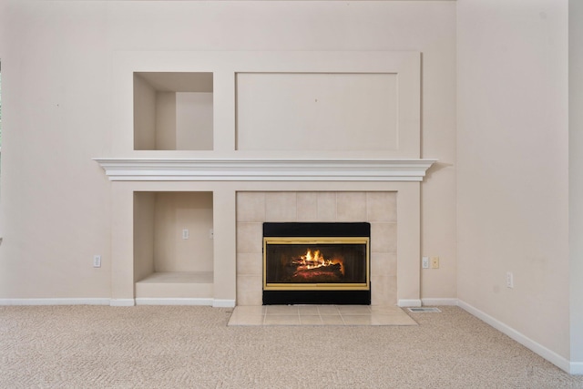 detailed view of carpet flooring, a tiled fireplace, and baseboards
