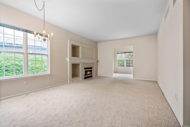 unfurnished living room featuring a chandelier, carpet flooring, baseboards, and a fireplace