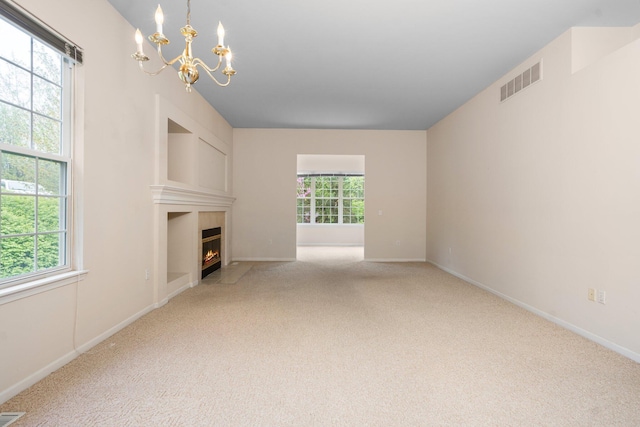 unfurnished living room with a chandelier, healthy amount of natural light, and carpet