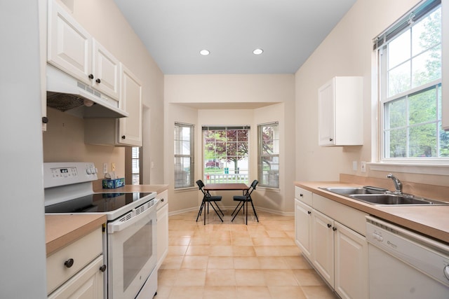 kitchen featuring white appliances, a sink, under cabinet range hood, baseboards, and recessed lighting