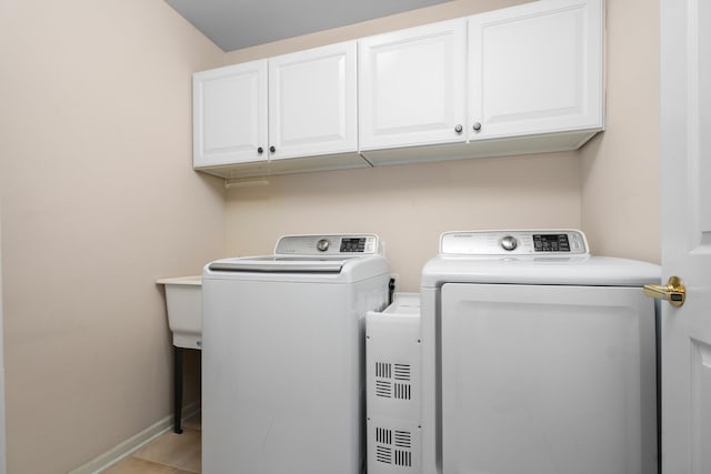washroom with separate washer and dryer, cabinet space, and baseboards