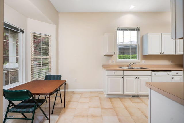 kitchen with a sink, white dishwasher, white cabinets, and recessed lighting