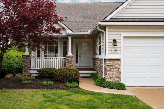 property entrance featuring a shingled roof, stone siding, a porch, and a garage