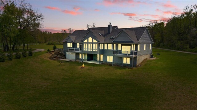 12150 Shaffer Rd, Davisburg, MI 48350 - back of house at dusk with a yard, a garage, a chimney, and a deck