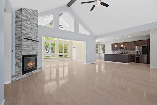 12150 Shaffer Rd, Davisburg, MI 48350 - unfurnished living room featuring a fireplace, beamed ceiling, light wood-style flooring, a ceiling fan, and high vaulted ceiling