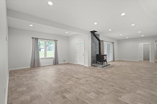12150 Shaffer Rd, Davisburg, MI 48350 - unfurnished living room with a wood stove, recessed lighting, light wood-style floors, and baseboards