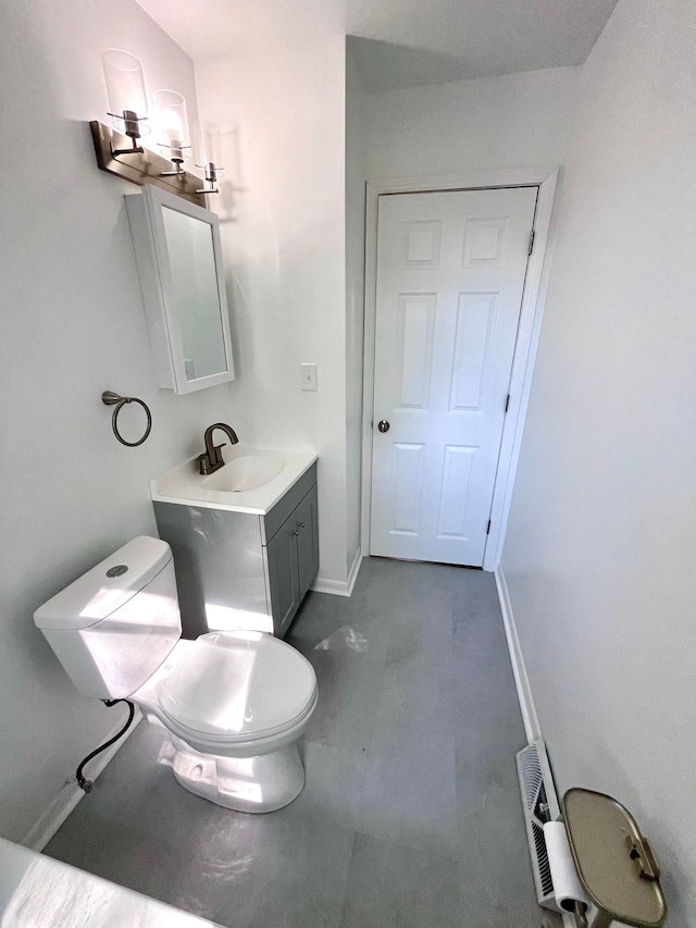 half bathroom featuring toilet, vanity, and baseboards