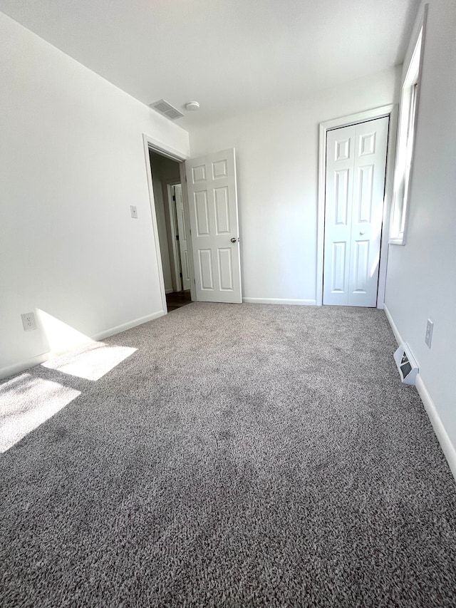 unfurnished bedroom featuring carpet, baseboards, and a closet