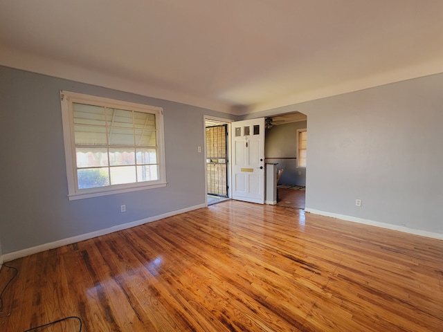 spare room featuring wood finished floors, baseboards, and arched walkways