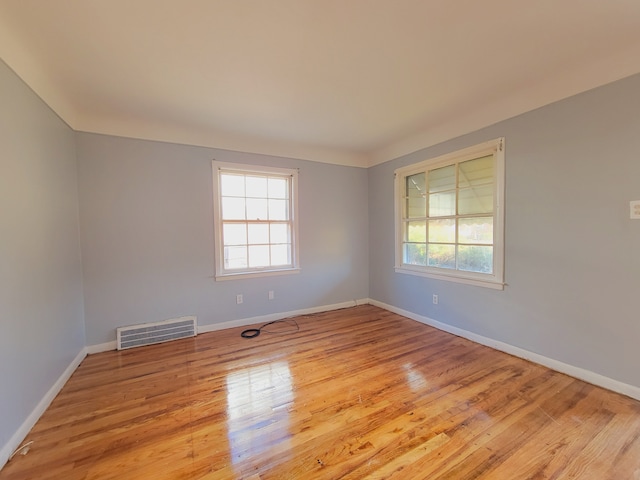 spare room featuring plenty of natural light, baseboards, and wood finished floors