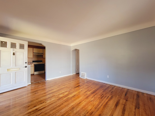 unfurnished living room featuring light wood-style floors, baseboards, and arched walkways