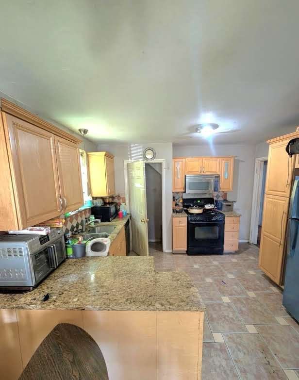 11301 Coyle St, Detroit, MI 48227 - kitchen featuring black appliances, a peninsula, a sink, light brown cabinetry, and light stone countertops
