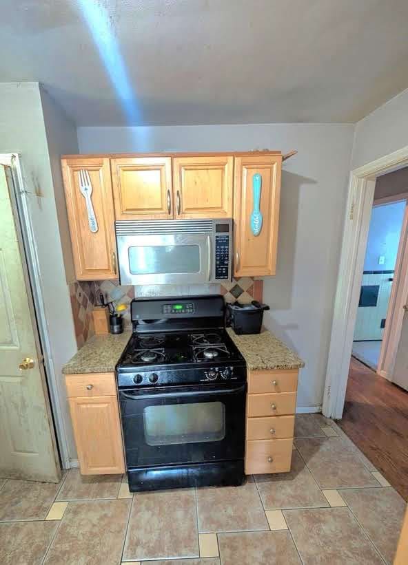 11301 Coyle St, Detroit, MI 48227 - kitchen featuring gas stove, stainless steel microwave, light brown cabinetry, and tasteful backsplash