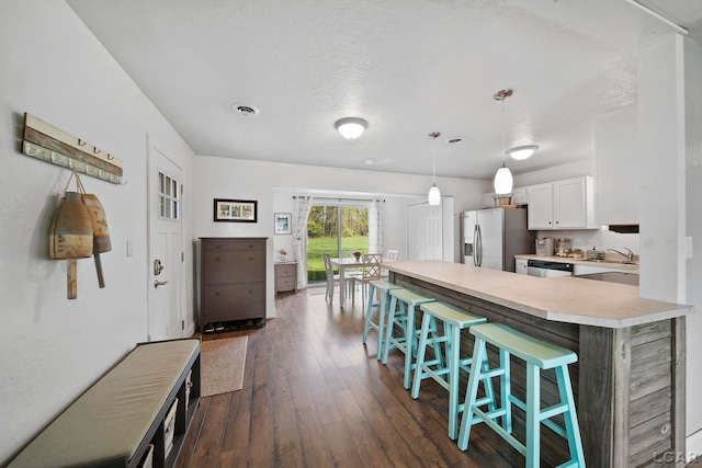 5541 Pleasant Valley Rd, Manitou Beach, MI 49253 - kitchen with stainless steel fridge, light countertops, a kitchen breakfast bar, dishwashing machine, and white cabinets