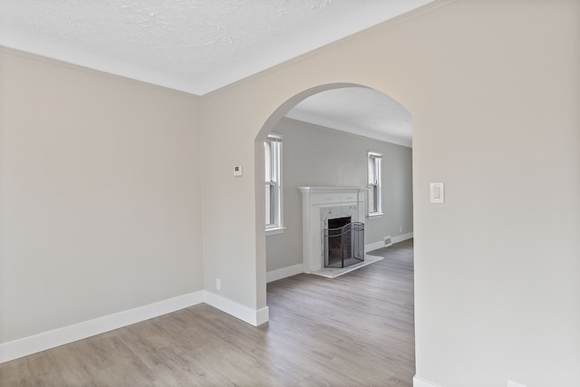 15470 Murray Hill St, Detroit, MI 48227 - unfurnished living room featuring ornamental molding, wood finished floors, baseboards, a textured ceiling, and arched walkways