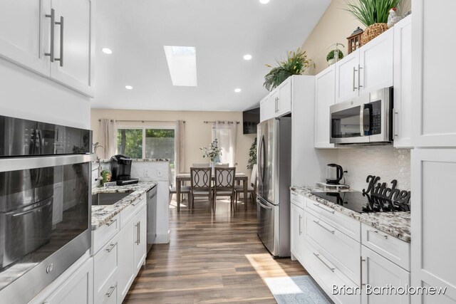 2657 Leffingwell Ave NE, Grand Rapids, MI 49525 - kitchen featuring stainless steel appliances, a skylight, recessed lighting, wood finished floors, and white cabinets
